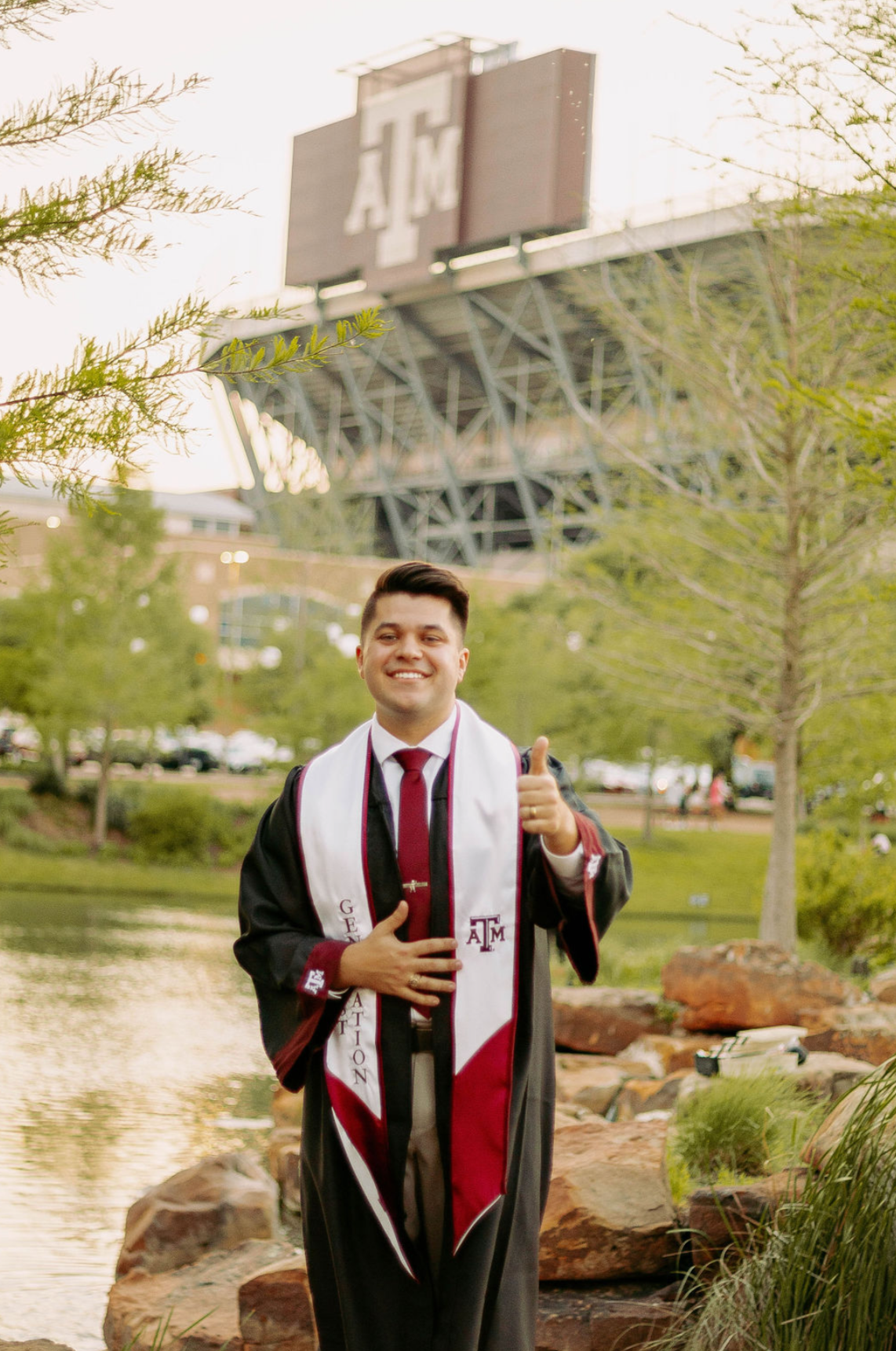 Braden Farrell in graduation regalia in front of Kyle Field at Texas A&M University