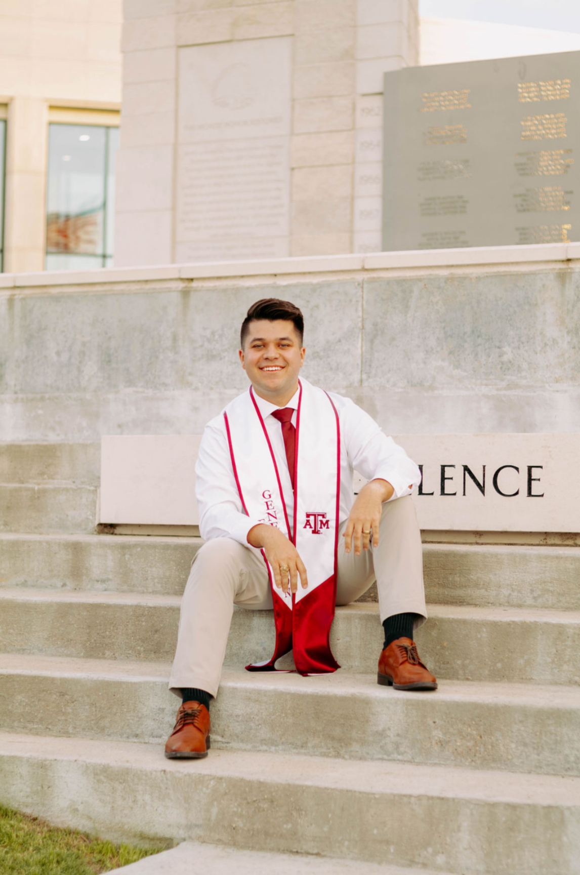 Braden Farrell wearing a Texas A&M graduation stole while seated on campus steps