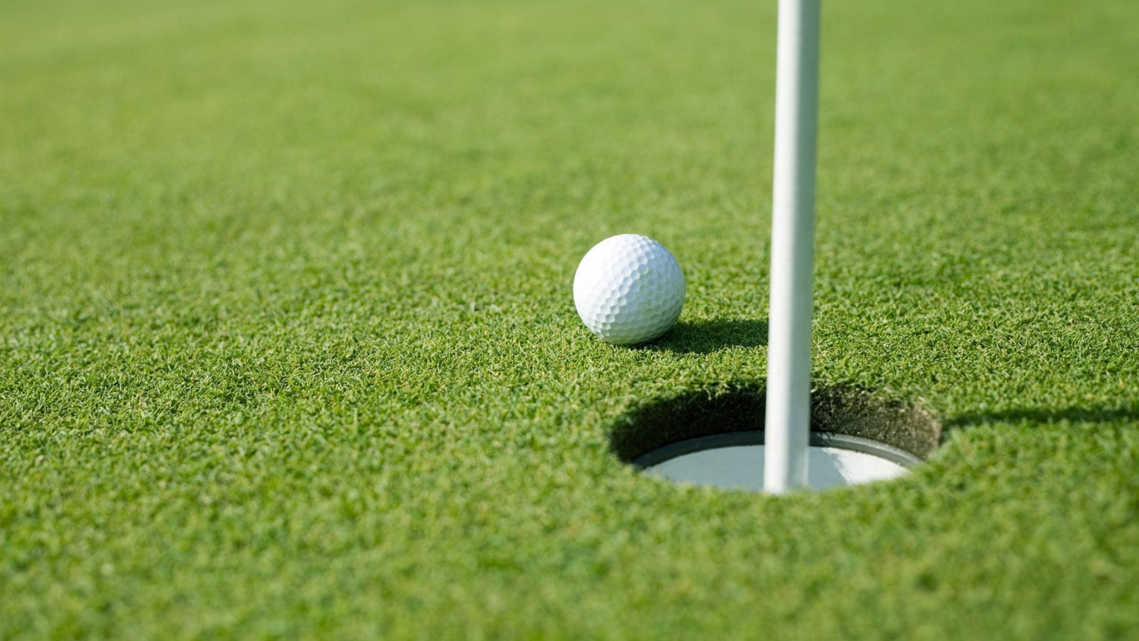 Golf ball near a putting green hole
